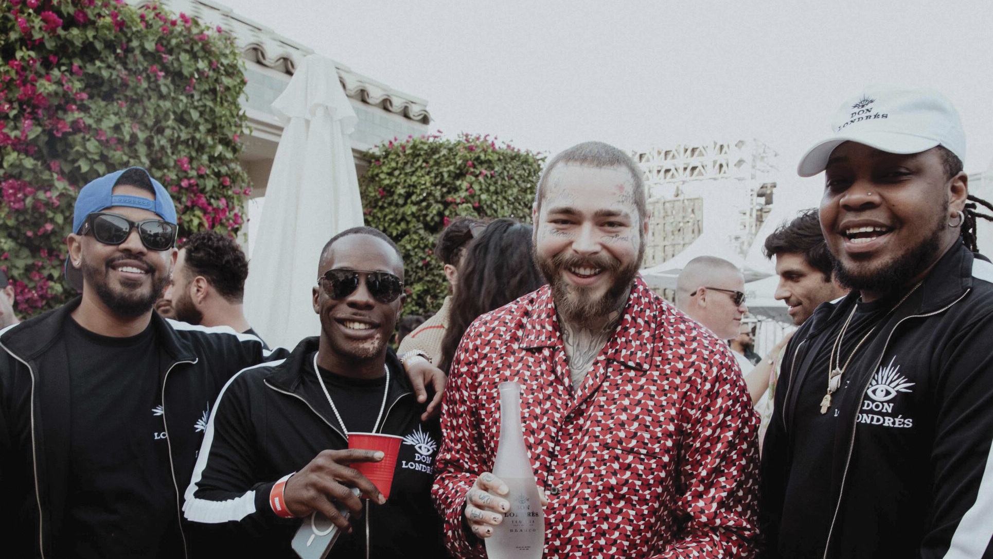 Group of friends celebrating at an outdoor event, one holding a bottle of Don Londrés tequila